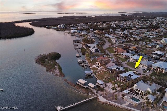 aerial view at dusk featuring a water view