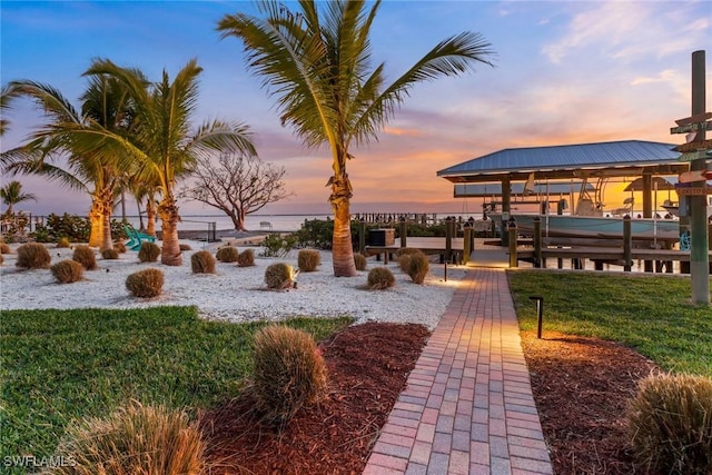 view of property's community featuring a boat dock, a yard, and a water view