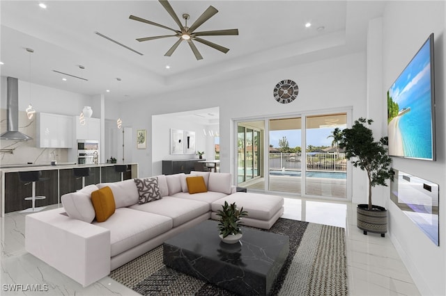 living room with a raised ceiling and ceiling fan