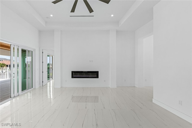 unfurnished living room featuring heating unit, ceiling fan, and a tray ceiling