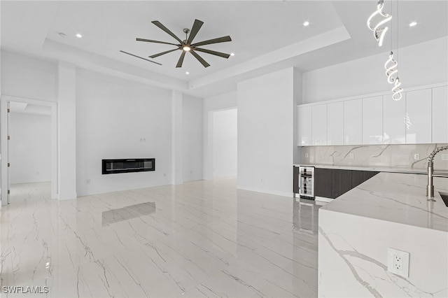 living room featuring a tray ceiling, heating unit, and ceiling fan