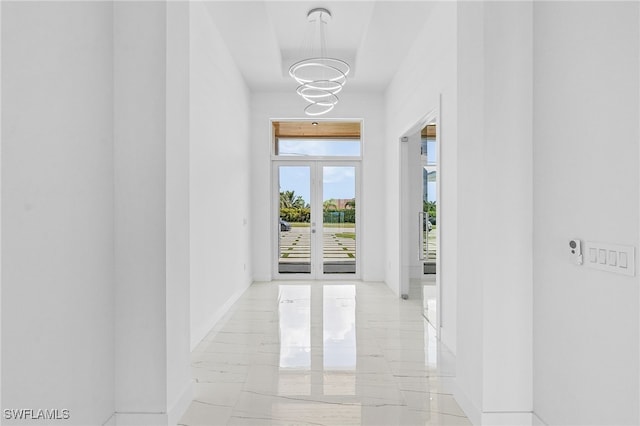 hallway featuring french doors and a notable chandelier