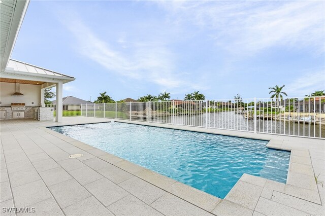 view of pool featuring an outdoor kitchen, a grill, and a water view