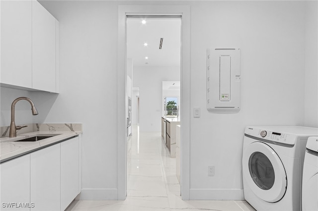 clothes washing area featuring cabinets, sink, and washer and dryer