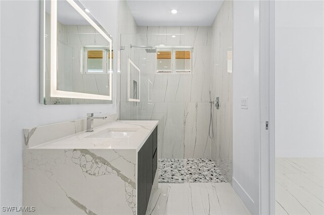 bathroom with a tile shower and vanity