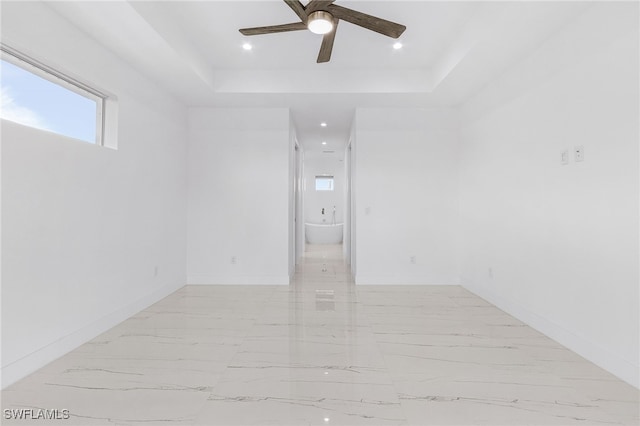 unfurnished room featuring a raised ceiling and ceiling fan