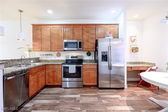 kitchen with decorative light fixtures, dark stone countertops, sink, and appliances with stainless steel finishes