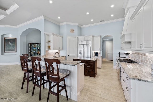 kitchen with a breakfast bar, high end appliances, decorative backsplash, light stone counters, and kitchen peninsula