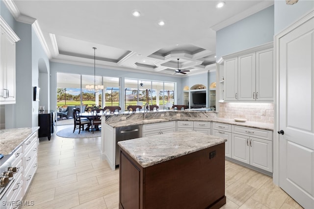 kitchen with kitchen peninsula, pendant lighting, ceiling fan with notable chandelier, and white cabinetry