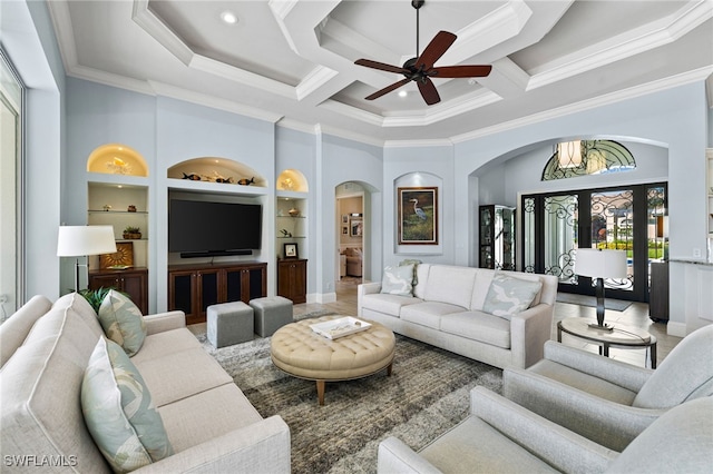 living room featuring ceiling fan, built in features, coffered ceiling, and ornamental molding