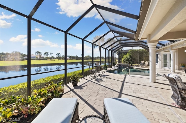 view of patio with a lanai, a pool with hot tub, and a water view