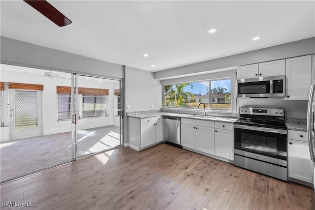 kitchen featuring sink, light wood-type flooring, white cabinetry, and stainless steel appliances