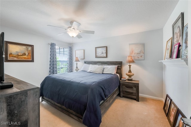 bedroom featuring ceiling fan, light colored carpet, and a textured ceiling