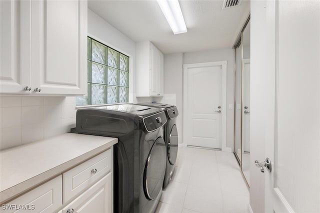 laundry area with washer and clothes dryer, cabinets, and light tile patterned floors