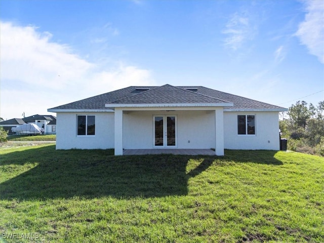 rear view of house featuring stucco siding, roof with shingles, and a yard