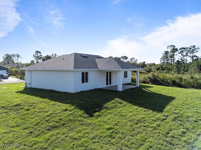 back of property featuring stucco siding, roof with shingles, a lawn, and a patio