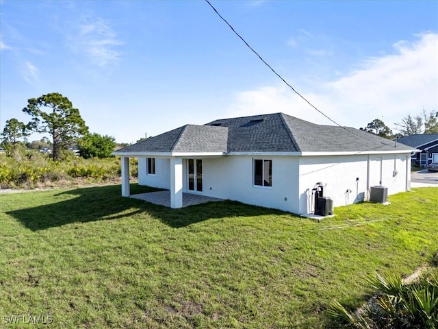 rear view of property with roof with shingles, stucco siding, a lawn, a patio area, and cooling unit