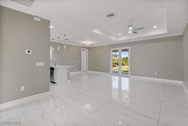 empty room with baseboards, a tray ceiling, visible vents, and crown molding