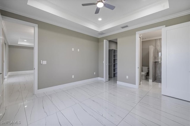 empty room featuring ornamental molding, marble finish floor, a tray ceiling, and baseboards