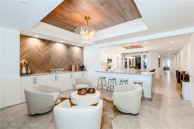 living room featuring a notable chandelier, wooden ceiling, and a tray ceiling