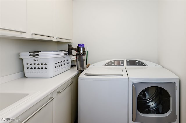 clothes washing area featuring cabinets and washing machine and dryer