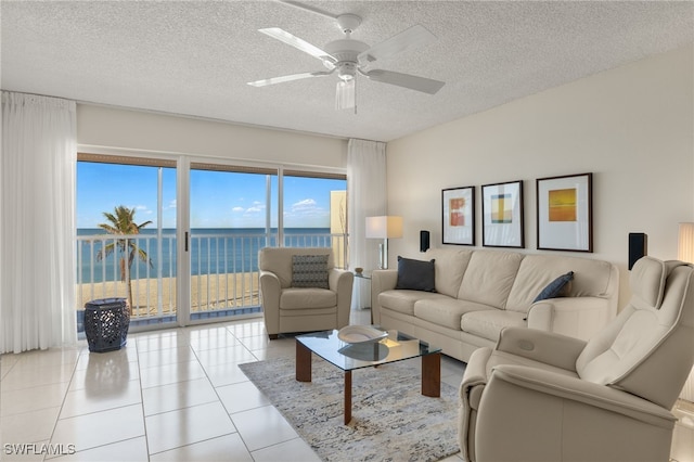 living room featuring ceiling fan, light tile patterned floors, a water view, and a textured ceiling