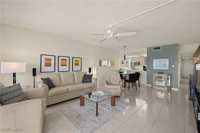 living room featuring light tile patterned floors, a textured ceiling, and ceiling fan