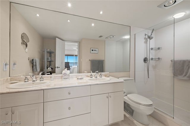 bathroom with a tile shower, vanity, and toilet