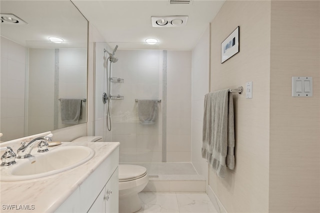 bathroom featuring tiled shower, vanity, and toilet