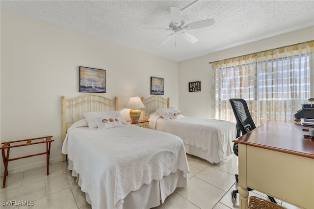 bedroom featuring ceiling fan, light tile patterned floors, and a textured ceiling