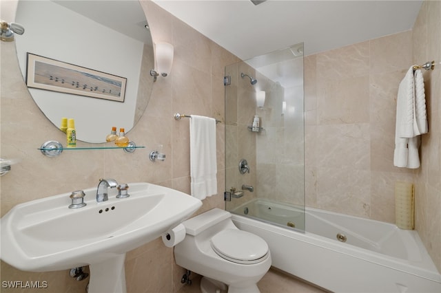 full bathroom with sink, tiled shower / bath combo, tile walls, and toilet