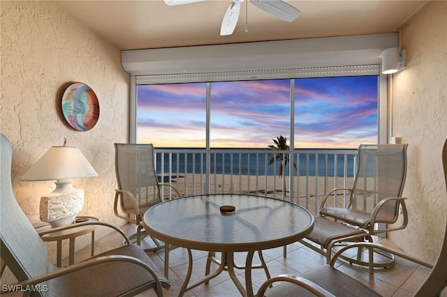 living area featuring light tile patterned floors, a water view, and ceiling fan