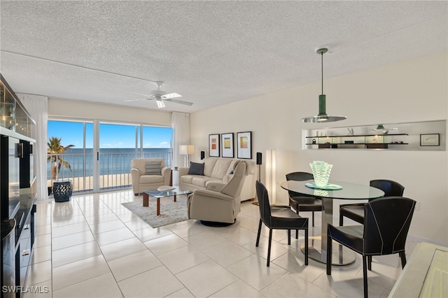 tiled living room with a textured ceiling, a water view, and ceiling fan