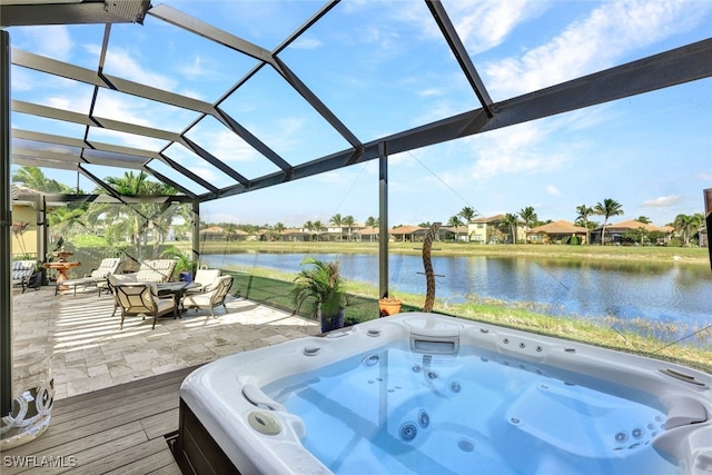 deck featuring a patio, a water view, an outdoor hot tub, and glass enclosure