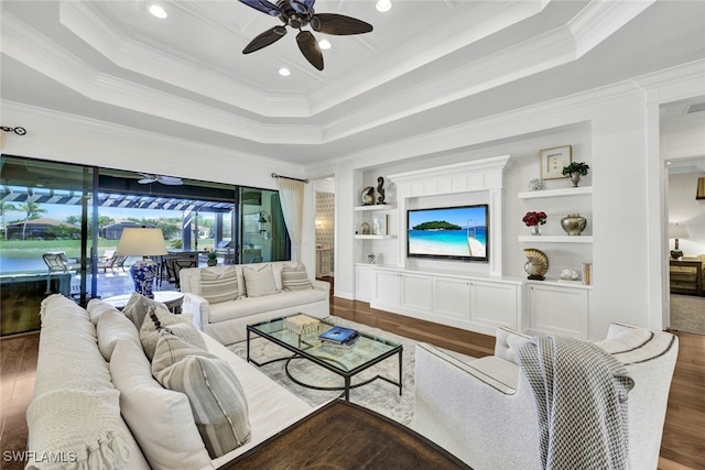 living room featuring wood-type flooring, a raised ceiling, built in features, and ceiling fan