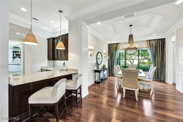 dining area with sink, dark hardwood / wood-style flooring, an inviting chandelier, and ornamental molding