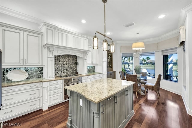 kitchen with pendant lighting, crown molding, light stone countertops, and a center island