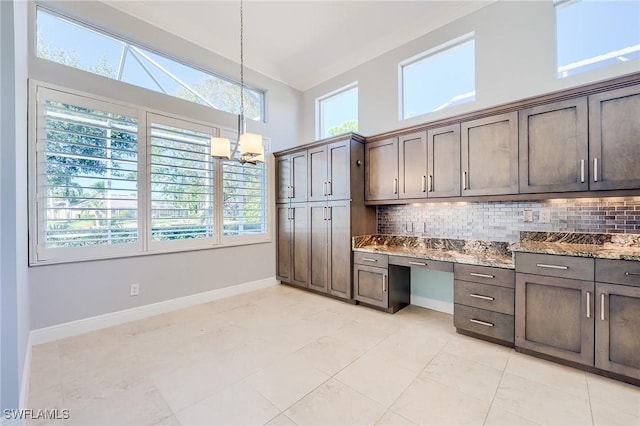 kitchen with pendant lighting, dark brown cabinetry, backsplash, and stone counters