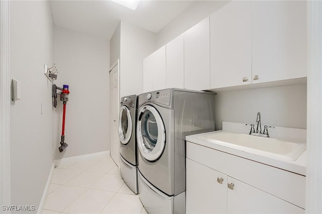 clothes washing area featuring washer and dryer, sink, light tile patterned floors, and cabinets