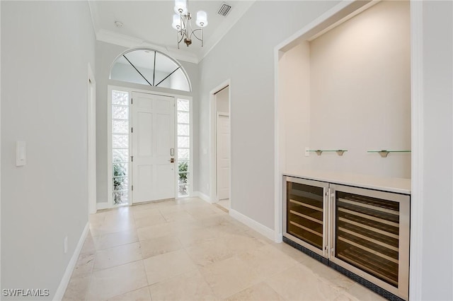 foyer featuring a chandelier, beverage cooler, and ornamental molding