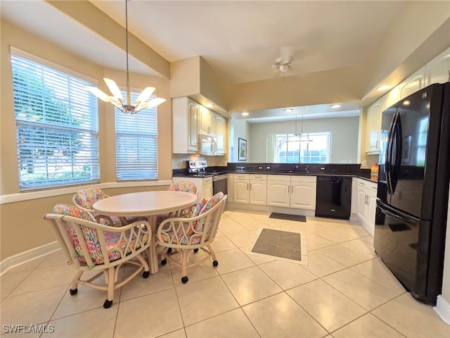 kitchen featuring black appliances, decorative light fixtures, and a wealth of natural light