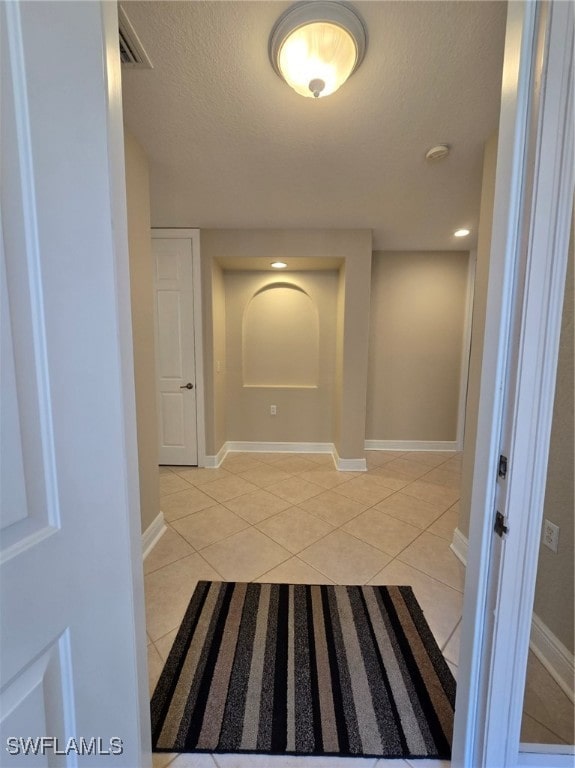 corridor featuring light tile patterned floors and a textured ceiling