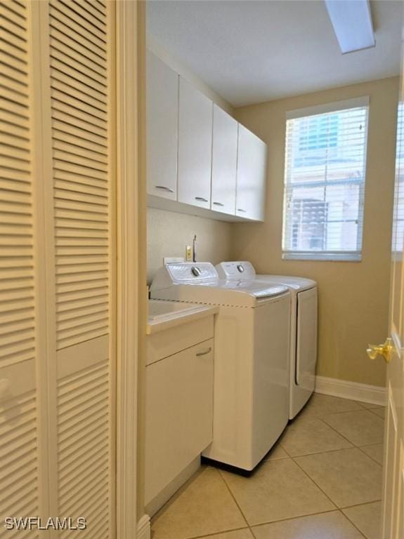 washroom featuring cabinet space, washer and dryer, baseboards, and light tile patterned flooring