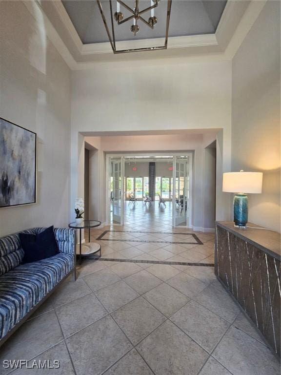 hall with a notable chandelier, french doors, light tile patterned flooring, baseboards, and a towering ceiling