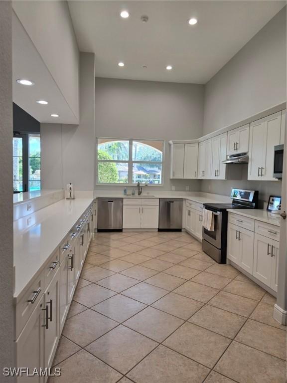 kitchen with sink, light tile patterned floors, white cabinetry, kitchen peninsula, and stainless steel appliances