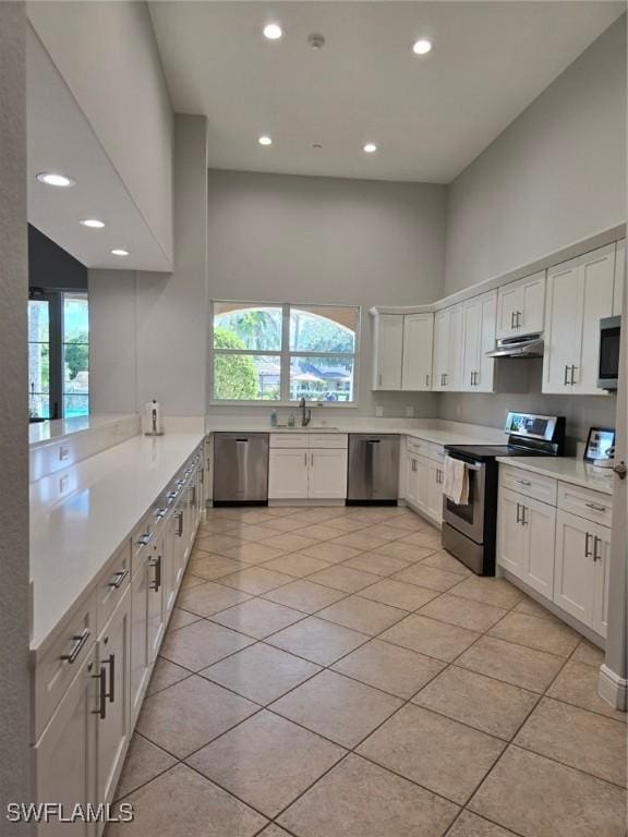 kitchen with under cabinet range hood, appliances with stainless steel finishes, light countertops, and a sink