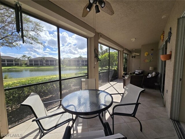 sunroom / solarium featuring ceiling fan and a water view