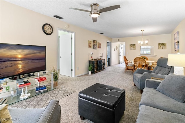 carpeted living room with a textured ceiling and ceiling fan with notable chandelier