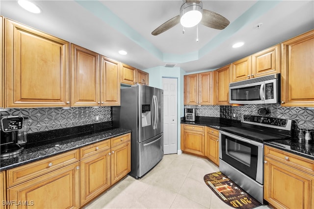 kitchen featuring stainless steel appliances, tasteful backsplash, and dark stone countertops