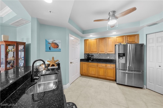 kitchen with dark stone counters, sink, stainless steel refrigerator with ice dispenser, decorative backsplash, and light tile patterned floors